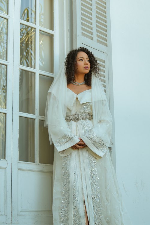 Une mariée en tenue marocaine traditionnelle dans un intérieur lumineux