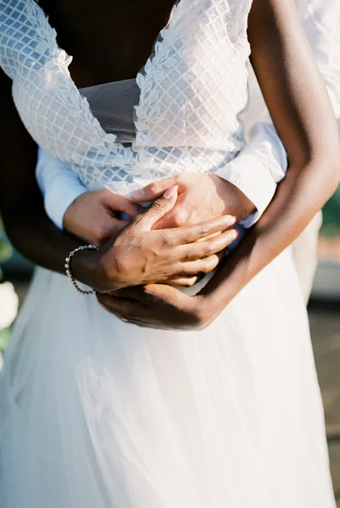 Les mains de deux mariés réunies dans un geste de tendresse.
