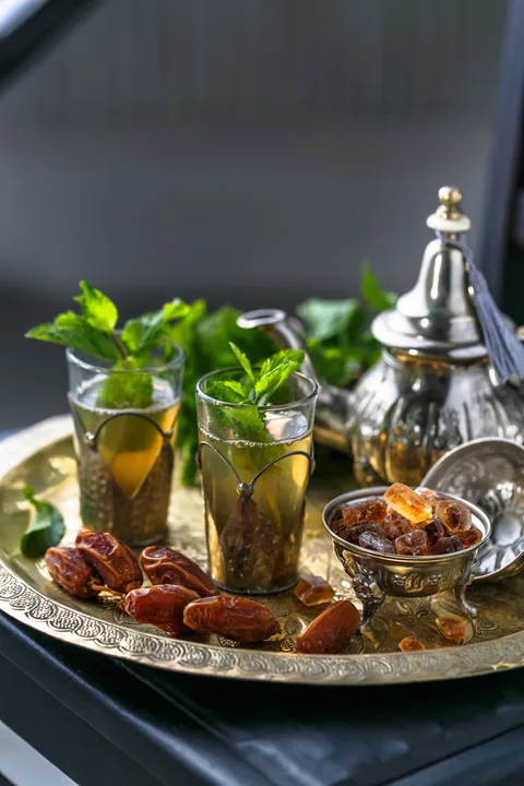 Thé marocain à la menthe, dattes et théière sur un plateau.