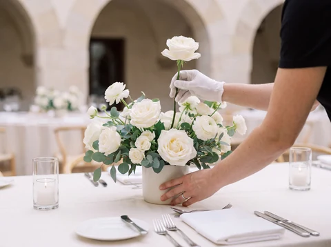 Illustration fictive : des fleurs blanches et du feuillage disposés sur une table de réception.